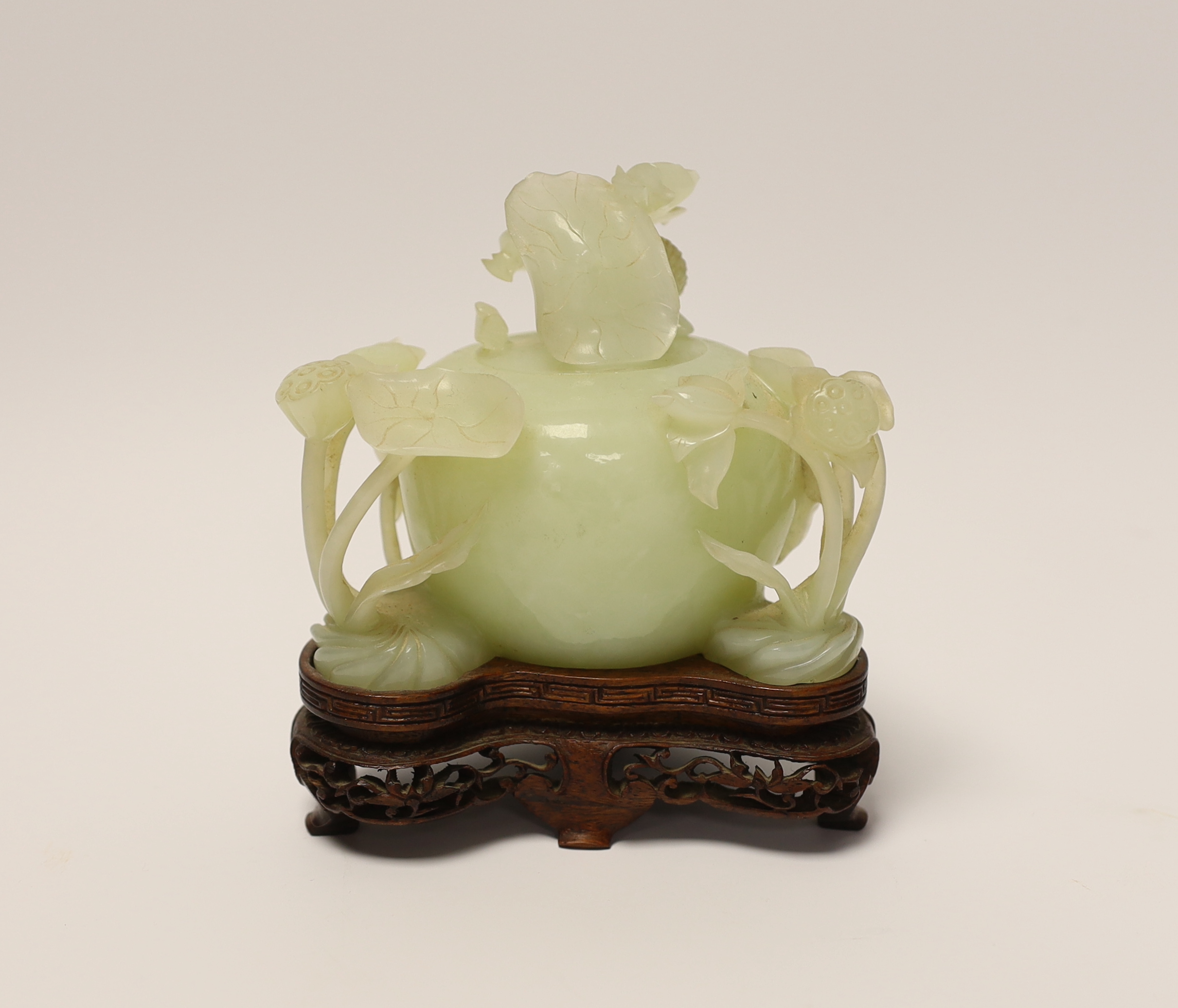 A Chinese carved bowenite jade ‘lotus’ water pot and cover on hardwood stand, 13cm